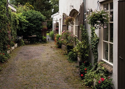 Over deze klinkers kuierden paarden/ – hun lijven loom van hard labeur – /terug naar de stal hier langszij/ stad omvatte niet enkel huizen maar ook een Vierwindenmolen/een stadsboerderij, akker en wei/ ik waai even binnen/ op dit voormalig erf/vind er een kleine oase/ een hoeve verbloemd. (Pien Storm van Leeuwen in de bundel Straten, Stromen en Struweel)